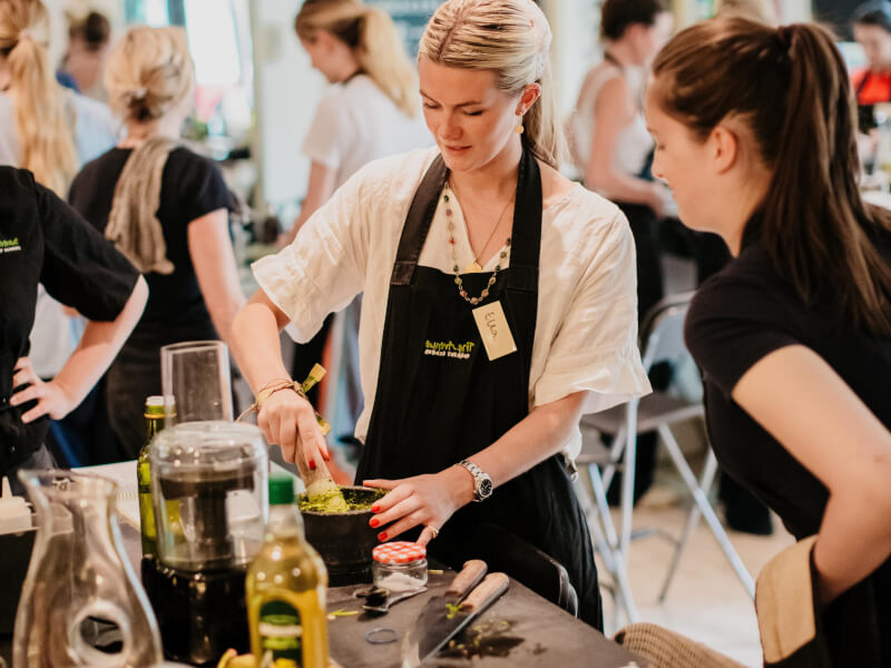 Two women in black aprons enjoying a cooking class